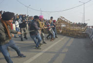 NEW DELHI, INDIA - JANUARY 26: Demonstrators removing police barricades while heading into the capital during a tractor rally on Republic Day, at Ghazipur on January 26, 2021 in New Delhi, India. Major scenes of chaos and mayhem at Delhi borders as groups of farmers allegedly broke barricades and police check posts and entered the national capital before permitted timings. Police used tear gas at Delhi's Mukarba Chowk to bring the groups under control. Clashes were also reported at ITO, Akshardham. Several rounds of talks between the government and protesting farmers have failed to resolve the impasse over the three farm laws. The kisan bodies, which have been protesting in the national capital for almost two months, demanding the repeal of three contentious farm laws have remained firm on their decision to hold a tractor rally on the occasion of Republic Day. (Photo by Sakib Ali/Hindustan Times via Getty Images)