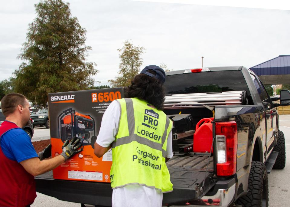 Lowe's employees load a newly purchased generator into the truck of Terry Storie on Tuesday morning in Lakeland. Storie said he also bought bought gallons of gas in portable containers.