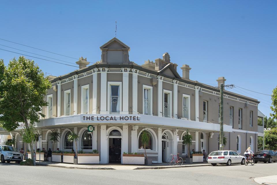 Exterior of a building on a street corner with a sign reading 'The Local Hotel'