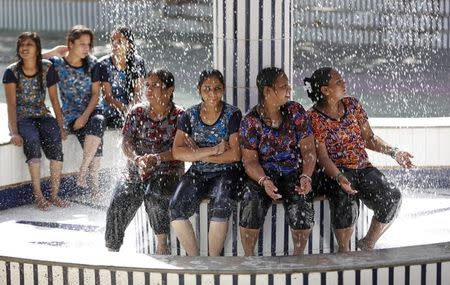 Women sit under a fountain to cool off at a water park on a hot summer day in Ahmedabad, India, May 3, 2016. REUTERS/Amit Dave