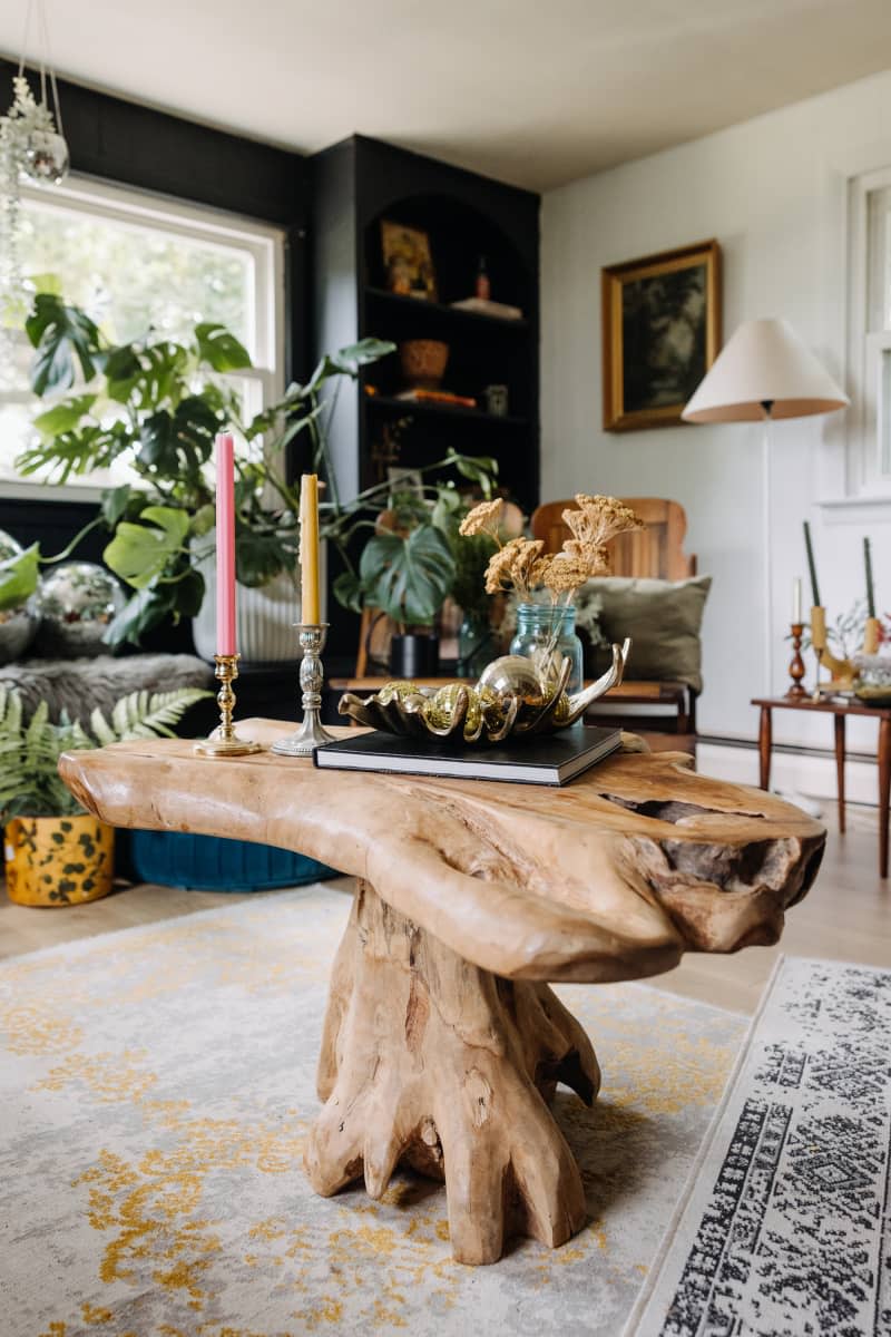 Wood edge coffee table in living room topped with taper candles and various decorative objectives.