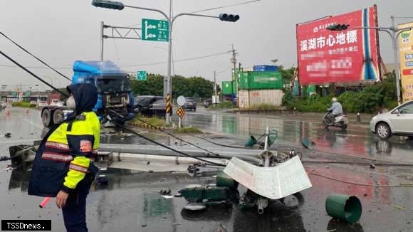 陳姓民眾駕駛營業貨運曳引車疑似因天雨路面打滑撞上分隔島號誌燈，導致號誌燈倒塌，波及等待左轉的轎車。（記者方一成攝）