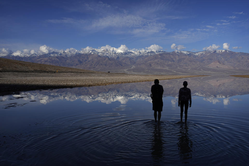 Vijay Parthasarathy, left, and Vinaya Vijay wade into water at Badwater Basin, Thursday, Feb. 22, 2024, in Death Valley National Park, Calif. The basin, normally a salt flat, has filled from rain over the past few months. (AP Photo/John Locher)