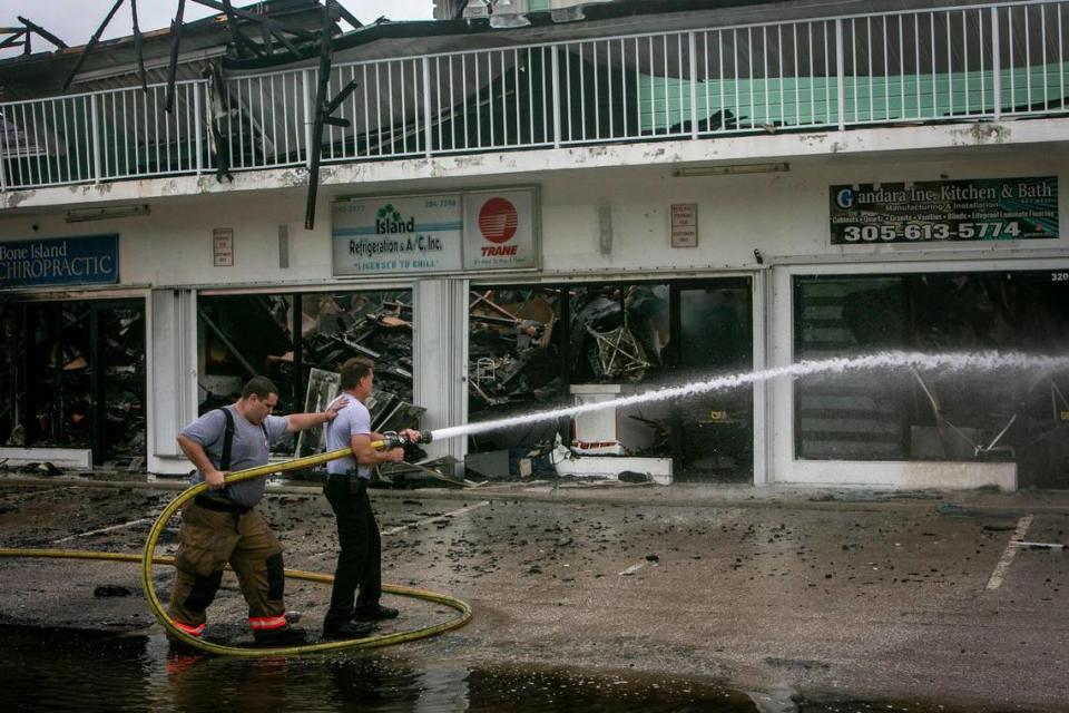 Key West firefighters pour water on the smoldering ruins of a building that caught fire on Flagler Avenue early Wednesday morning, Sept. 28, 2022, in Key West, Florida.