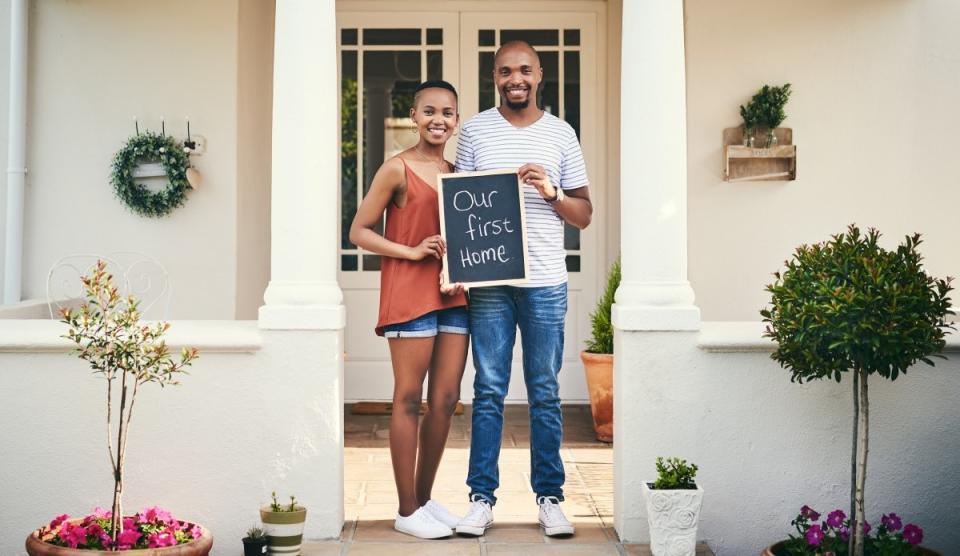 happy smiling young couple holding our first home sign