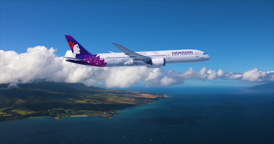 A Hawaiian Airlines Boeing 787-9 Dreamliner flying above an island. The 300-seat aircraft is painted white and purple, the colors of the airline.