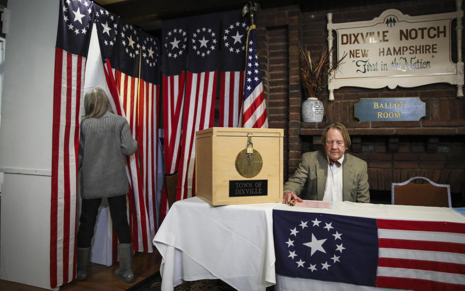 Dixville Notch resident Deborah Tillotson, left, enters a voting booth while her husband Tom Tillotson moderates the votes in Dixville Notch, New Hampshire, on Feb. 11, 2020.  / Credit: Erin Clark/The Boston Globe via Getty Images