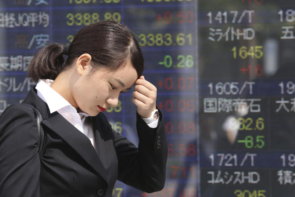 A woman walks by an electronic stock board of a securities firm in Tokyo, Tuesday, Oct. 1, 2019. Shares rose in Asia on Tuesday, with markets in Hong Kong and Shanghai closed for a national day holiday. (AP Photo/Koji Sasahara)