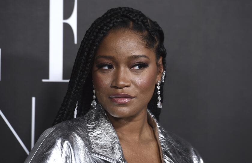 Keke Palmer posing in a silver jacket and dangly earrings.