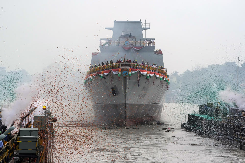 FILE- Confetti and smoke in the colors of the Indian national flag mark the entry of INS Vindhyagiri, a new warship for the Indian navy, into the Hooghly river in Kolkata, India, Aug. 17, 2023. India has long focused its defense policy on its land borders with rivals Pakistan and China but is now beginning to flex its naval power in international waters, including anti-piracy patrols and a deployment close to the Red Sea to protect ships from attacks.(AP Photo/Bikas Das, file)