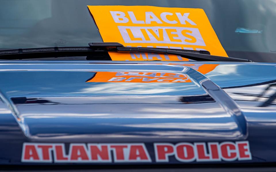 A Black Lives Matter sign is placed on a police car near the scene of an overnight police shooting that left a man dead at a Wendy's restaurant in Atlanta - ERIK S LESSER/EPA-EFE/Shutterstock