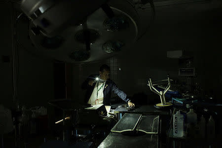 A nurse uses light from a phone while he looks for material in an out-of-use operating room of the Padre Justo hospital, during a blackout in Rubio, Venezuela March 14, 2018. Picture taken March 14, 2018. REUTERS/Carlos Eduardo Ramirez TPX IMAGES OF THE DAY