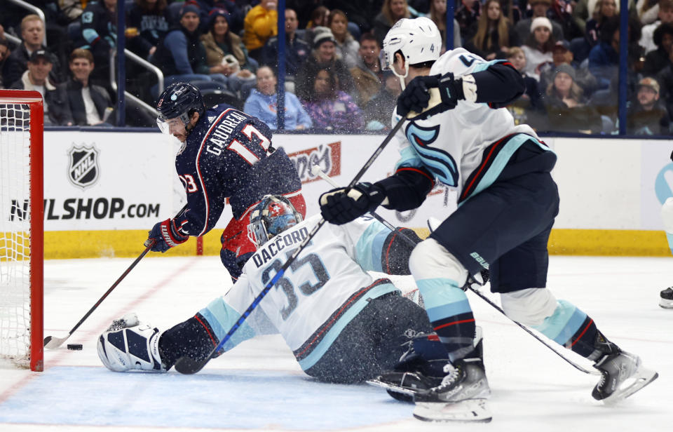 Columbus Blue Jackets forward Johnny Gaudreau, left, settles the puck in front of Seattle Kraken goalie Joey Daccord, center, and defenseman Justin Schultz during the second period NHL hockey game in Columbus, Ohio, Saturday, Jan. 13, 2024. (AP Photo/Paul Vernon)