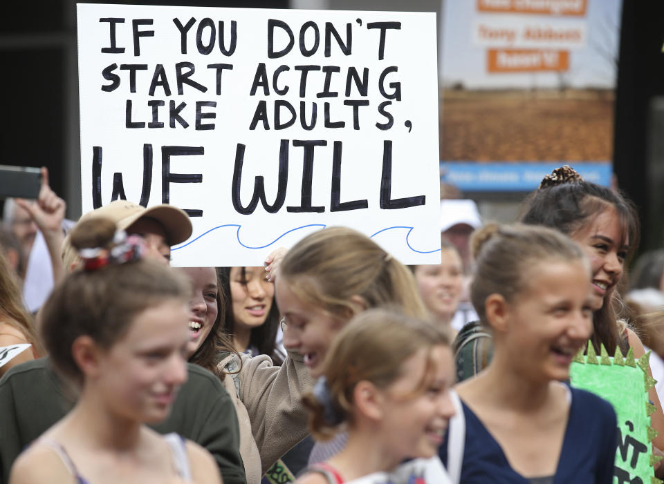 Picturee of children at a Climate Strike rally in 2019, with one teen holding a sign saying "If you don't start acting like adults, we will"
