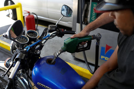 A gas station worker pumps gas into a motorbike at a gas station of the Venezuelan state-owned oil company PDVSA in Caracas, Venezuela August 17, 2018. REUTERS/Marco Bello