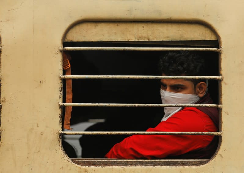 A boy with a covered face looks through a window of a train in New Delhi