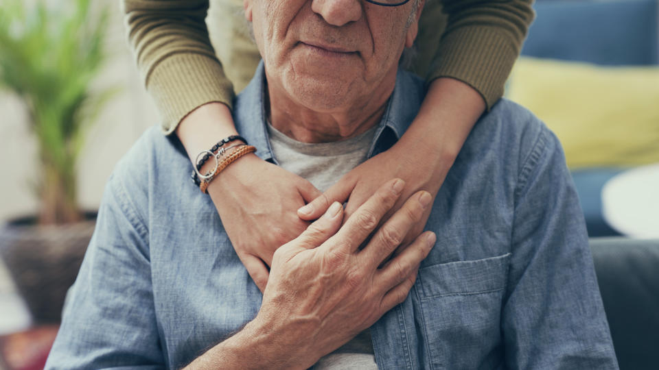 Persone places their comforting hands on the shoulders of an older man. (Photo via Getty Images)