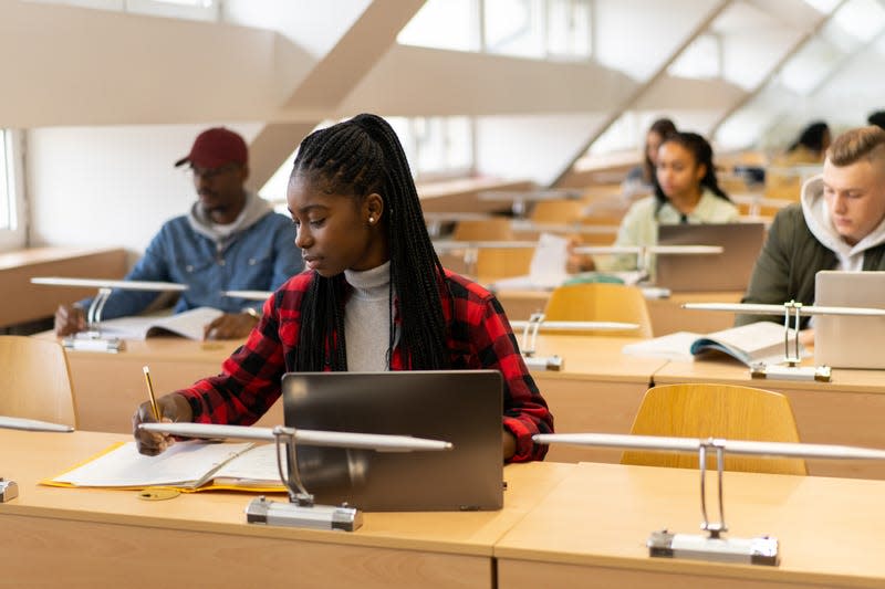 Young African American student writing in classroom - Photo: Vladimir Vladimirov (Getty Images)