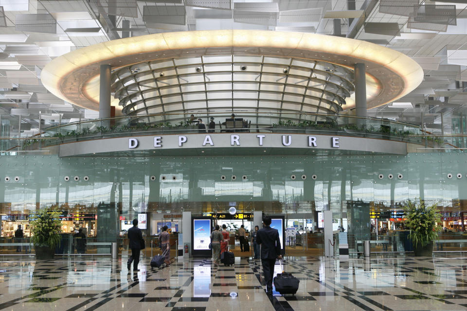 FILE - In this Oct. 8, 2008, file photo, passengers walk through the departure hall at the Changi International Airport in Singapore. Drones buzzing around Singapore's Changi Airport have caused the delay or diversion of 63 flights in the past week, triggering an official investigation and raising questions about the motives of the offenders. Regulators said Tuesday, June 25, 2019, that 18 flights at the airport were delayed and seven were diverted the night before "due to bad weather and unauthorized drone activities."(AP Photo/Wong Maye-E, File)