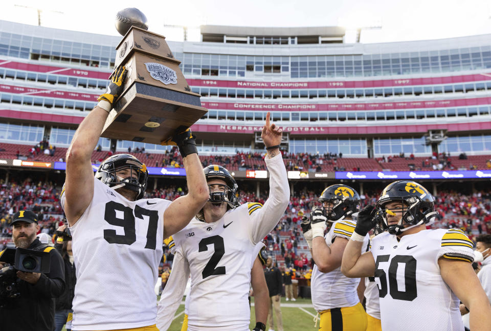 Iowa's Zach VanValkenburg (97) hoists the Heroes Trophy while celebrating with teammates Ryan Gersonde (2) and Louie Stec (50) following their victory over Nebraska in an NCAA college football game Friday, Nov. 26, 2021, at Memorial Stadium in Lincoln, Neb. (AP Photo/Rebecca S. Gratz)