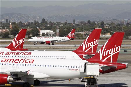A Virgin America jet takes off past other aircraft parked at Terminal 3 as the terminal begins to reopen the day after a shooting incident occurred at Los Angeles airport (LAX), California November 2, 2013. REUTERS/David McNew