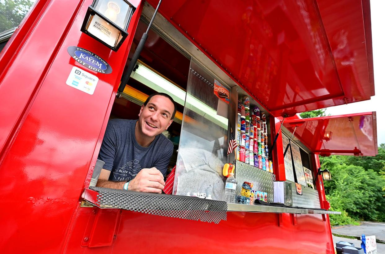 GRAFTON - Best in Show Hot Dogs owner Justin Wnukowski enjoys the cooler air as he sticks his head out of his (roughly) 6-by-10-foot stand at 80 Worcester St. Wednesday. Wnukowski, who has owned the tiny, cherry red business since May of last year, says that Tuesday, "was the hottest day since we've been open. This is perfect!"