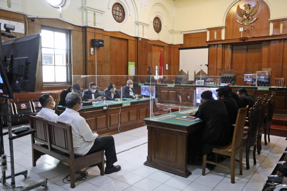 Arema FC Organizing Committee chair Abdul Haris, second left, the club's security chief Suko Sutrisno, far left, sit on the defendant's chair during their sentencing hearing at a district court in Surabaya, East Java, Indonesia, Thursday, March 9, 2023. The soccer club organizer and its chief of security were jailed by the Indonesian court on Thursday on charges of negligence leading to the deaths of 135 people when police fired tear gas inside a stadium last October, setting off a panicked run for the exits. (AP Photo/Trisnadi)