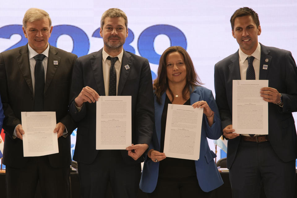 Sports Ministers, from left, Uruguay's Sebastian Bauza, Argentina's Matias Lammens, Chile's Alexandra Benado and Paraguay's Diego Galeano hold up documents they signed at the National Stadium to create the "Corporation Juntos 2030," the organization that will create their joint-bid to host the 2030 World Cup soccer tournament, in Santiago, Chile, Friday, Nov. 11, 2022. (AP Photo/Esteban Felix)