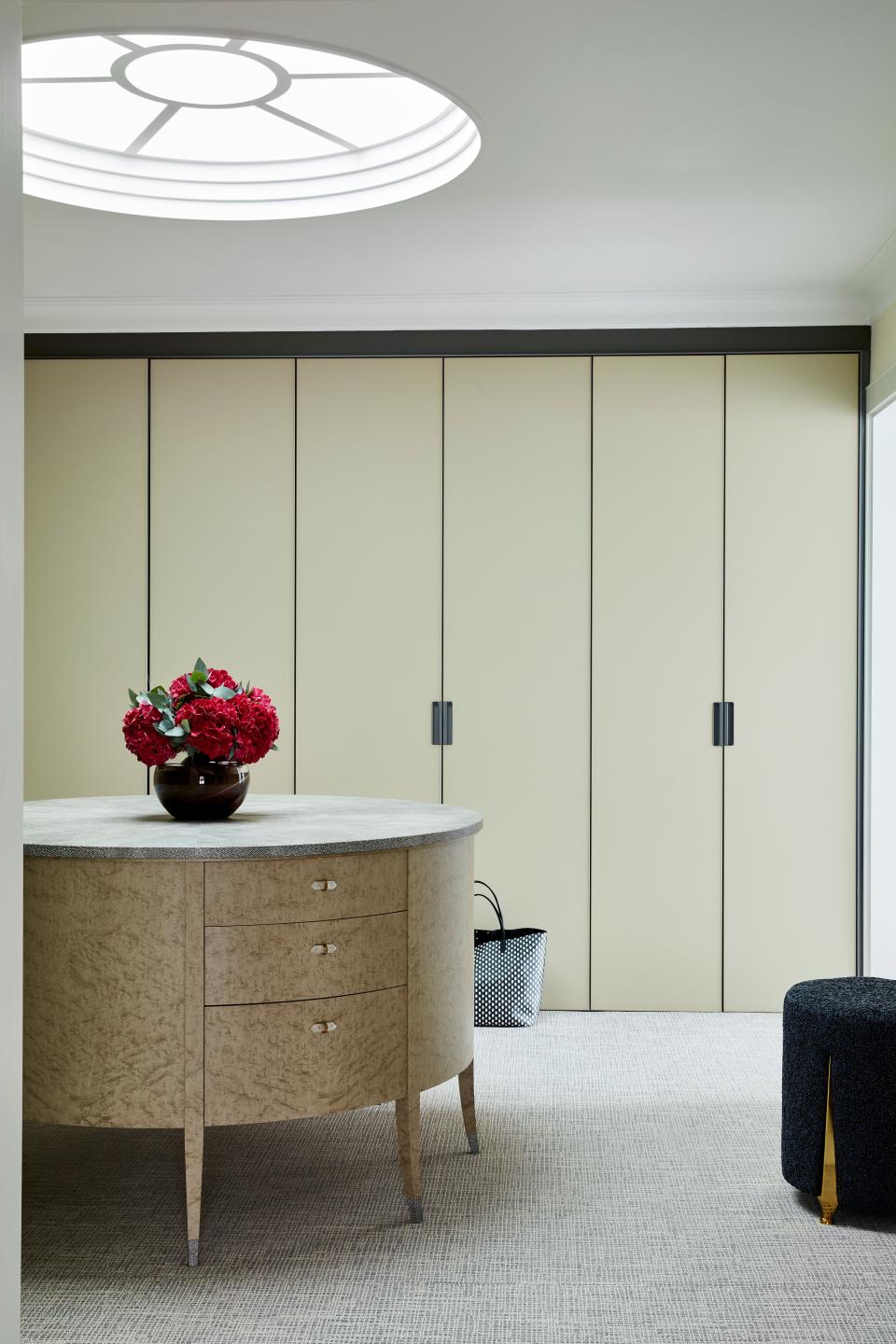 As there are no windows in this dressing room, LyonsKelly introduced a circular skylight above the shagreen-topped island made by Zelouf & Bell. The matte glass wardrobes are by Rimadesio for Minima while the rug is from Stark Carpet.