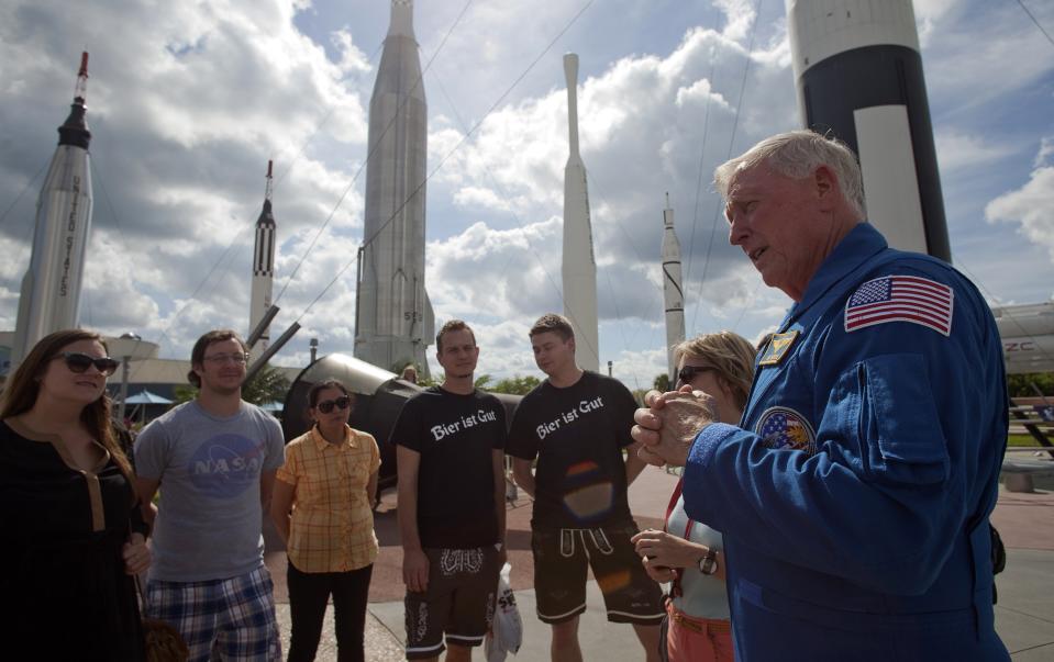 Retired astronaut Jon McBride (R) talks with visitors taking part in a tour at the 'Rocket Garden' of the Kennedy Space Center in Cape Canaveral, Florida October 2, 2013. The U.S. government shutdown has caused the standard bus tours to be suspended, but the center has added several other opportunities for tourists. REUTERS/Michael Brown (UNITED STATES - Tags: BUSINESS SCIENCE TECHNOLOGY)