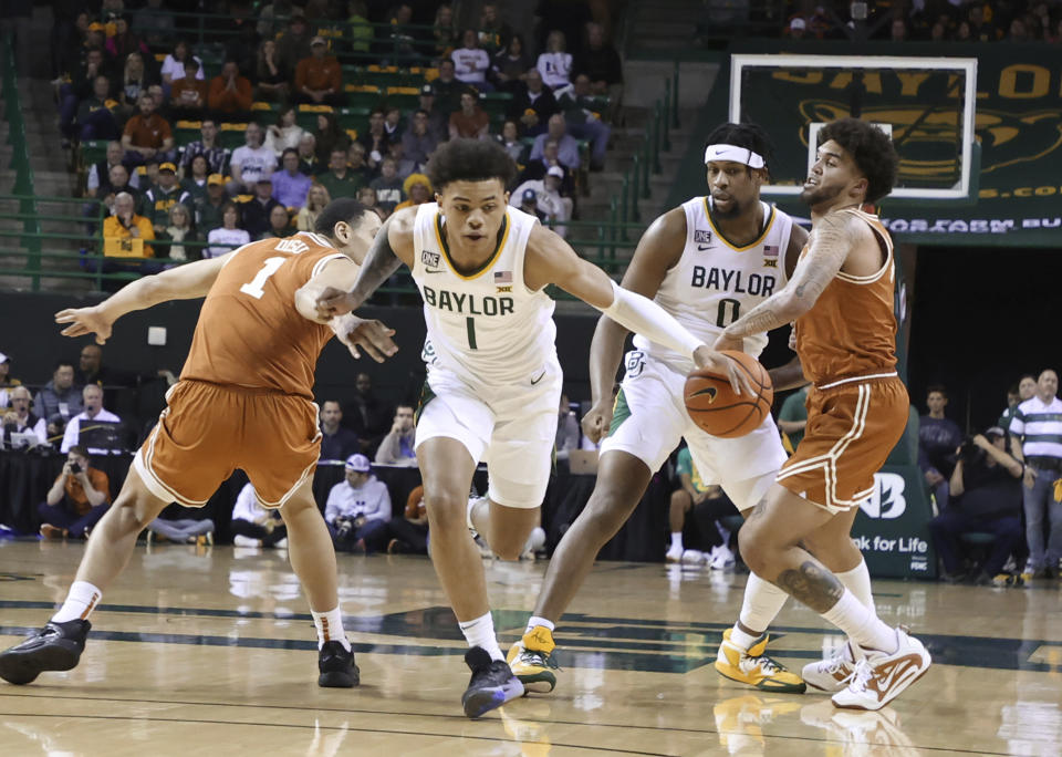 Baylor guard Keyonte George (1) loses the ball while driving through Texas forward Dylan Disu (1) and Timmy Allen (0) in the first half of an NCAA college basketball game, Saturday, Feb. 25, 2023, in Waco, Texas. (Rod Aydelotte/Waco Tribune-Herald via AP)