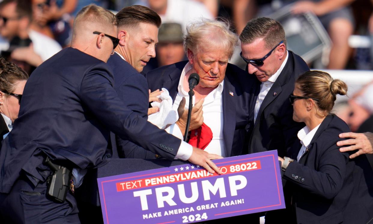 <span>Donald Trump is helped off the stage after an assassination attempt at a campaign rally in Butler, Pennsylvania, on Saturday.</span><span>Photograph: Gene J Puskar/AP</span>