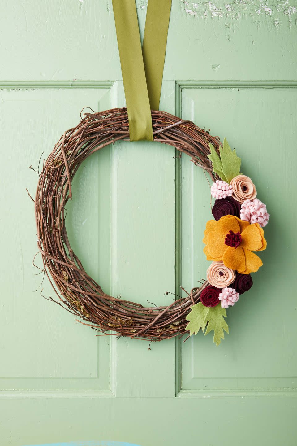 felt flowers and leaves on a grapevine wreath form