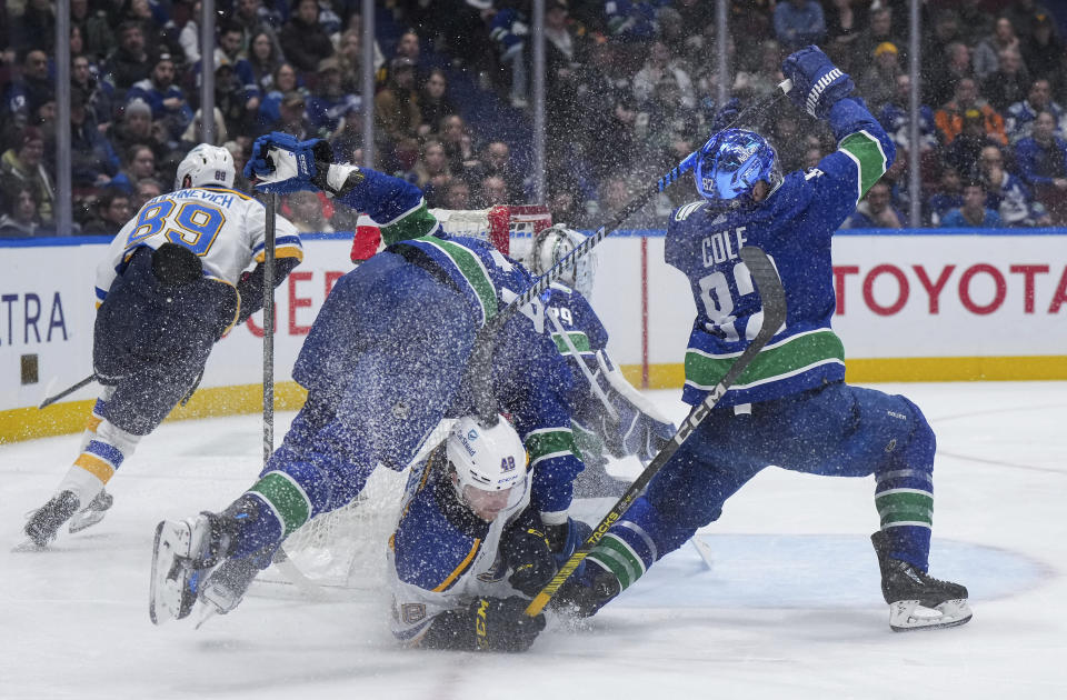 St. Louis Blues' Scott Perunovich (48) collides with Vancouver Canucks' Noah Juulsen, left, and Ian Cole, right, during the second period of an NHL hockey game Wednesday, Jan. 24, 2024, in Vancouver, British Columbia. (Darryl Dyck/The Canadian Press via AP)