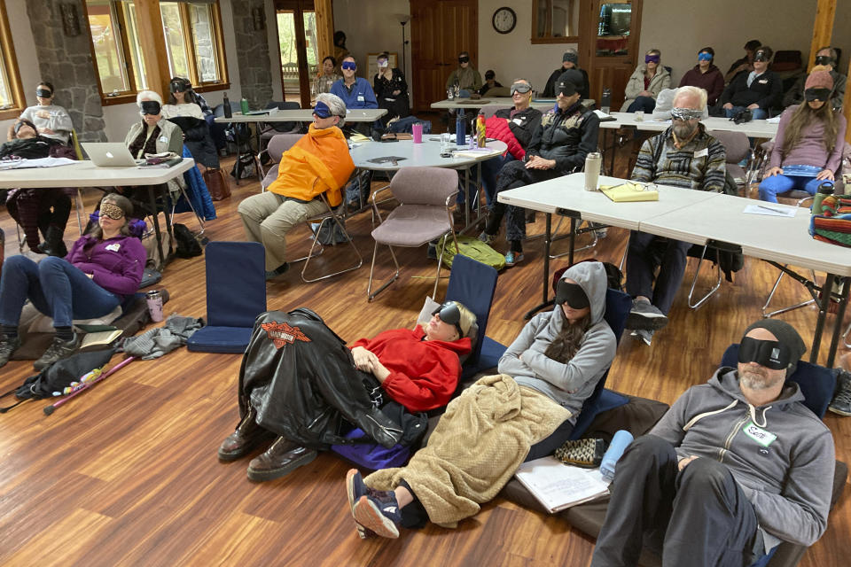 Psilocybin facilitator students sit with eye masks on while listening to music during an experiential activity at a training session near Damascus, Ore., on Dec. 2, 2022. They are being trained in how to accompany patients tripping on psilocybin as Oregon prepares to become the first state in America to offer controlled use of the psychedelic mushroom to the public. (AP Photo/Andrew Selsky)