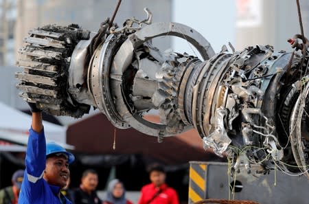 A worker assists his colleague during the lifting of a turbine engine of the Lion Air flight JT610 jet, at Tanjung Priok port in Jakarta