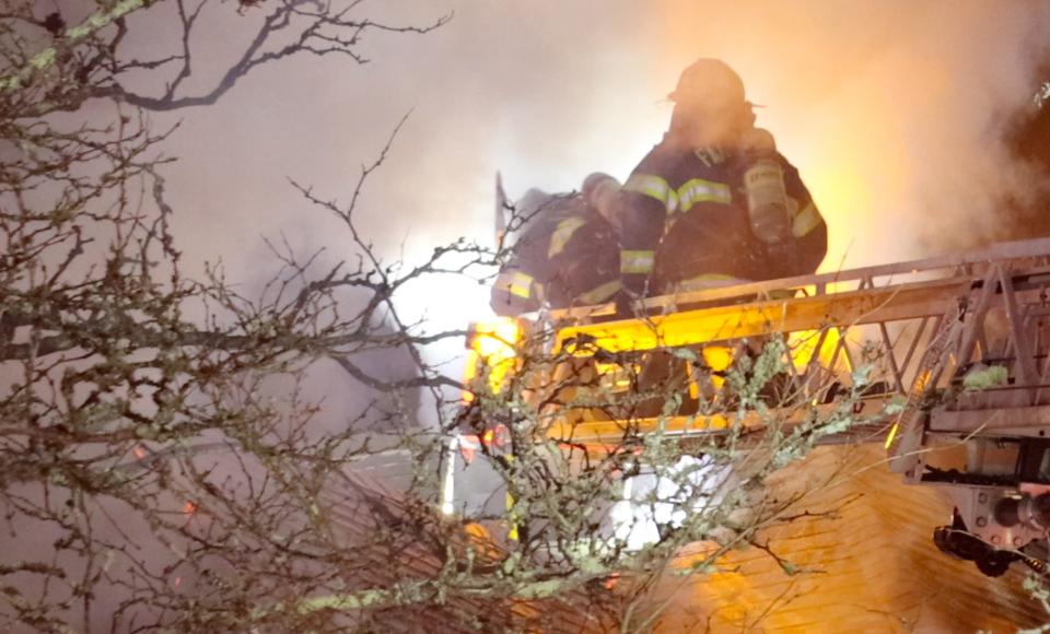 A firefighter battles flames Monday from above the second floor at 172 Main St. in Falmouth.