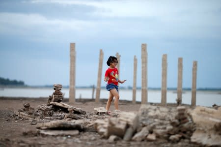 A girl walks through the ruins of a Buddhist temple which has resurfaced in a dried-up dam due to drought, in Lopburi, Thailand