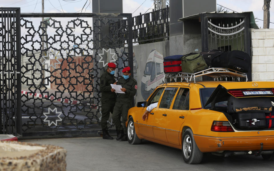 Hamas security officers check the list of the passengers while waiting at the gate to cross the border to the Egyptian side of Rafah crossing, in Rafah, Gaza Strip, Tuesday, Aug. 11, 2020. Egypt reopened Rafah Crossing for three days starting Tuesday for humanitarian cases in and out of the Gaza Strip, including medical patients and people who had Egyptian and international citizenship. The border was closed since March. (AP Photo/Adel Hana)