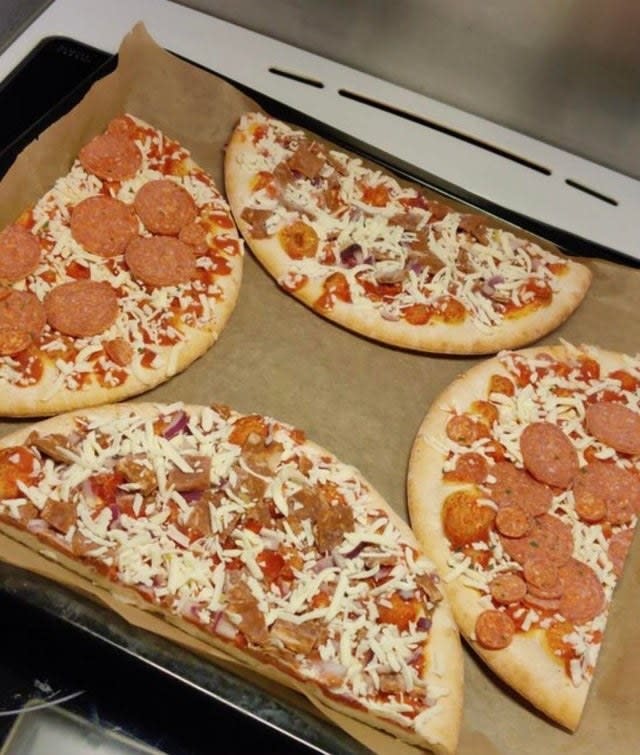 Four halves of frozen pizza on a sheet pan.