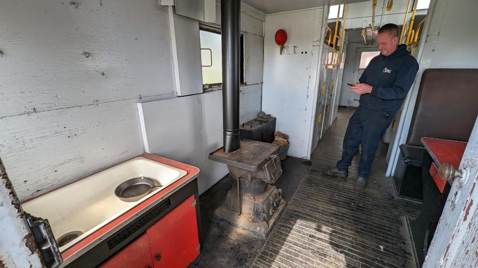 Mark Koppenhaver inside the caboose with a sink, coal stove and work table.