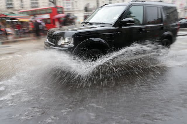 A car drives through a puddle in central London, as heavy rain and grey skies have marred the astronomical beginning of summer.