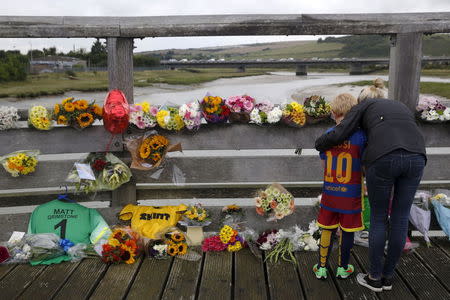 A woman and child hold each other in front of flowers near to the location where a Hawker Hunter fighter jet crashed onto the A27 road at Shoreham near Brighton, Britain August 24, 2015. REUTERS/Luke MacGregor