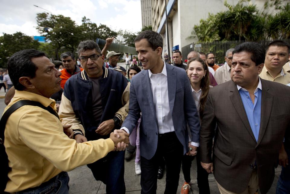 Juan Guaido, center, President of the Venezuelan National Assembly greets supporters upon his arrival to attend a public session with members of the opposition, at a street in Caracas, Venezuela, Friday, Jan. 11, 2019. The head of Venezuela's opposition-run congress says that with the nation's backing he's ready to take on Nicolas Maduro's presidential powers and call new elections.(AP Photo/Fernando Llano)