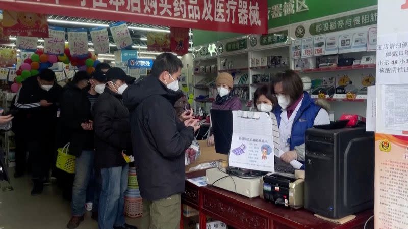 Varias personas hacen cola para comprar medicamentos en una farmacia de Pekín, China