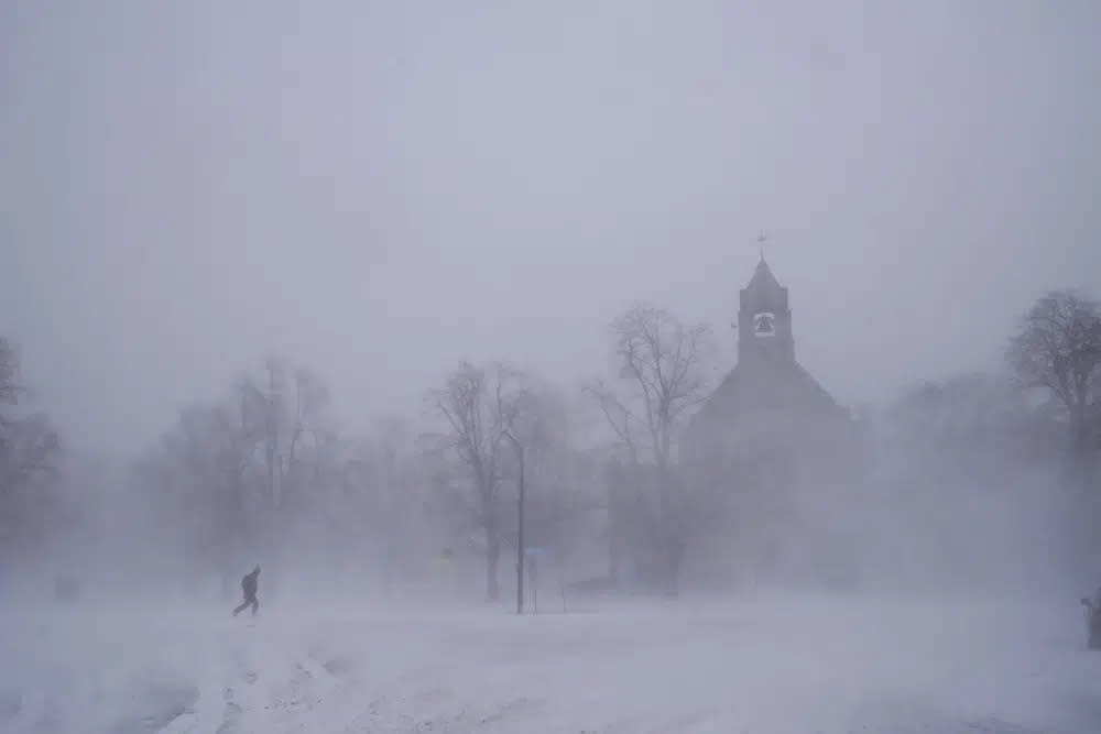 A lone pedestrian in snow shoes makes his way across Colonial Circle as St. John’s Grace Episcopal Church rises above the blowing snow amid blizzard conditions in Buffalo, N.Y. on Saturday, Dec. 24, 2022. (Derek Gee/The Buffalo News via AP)