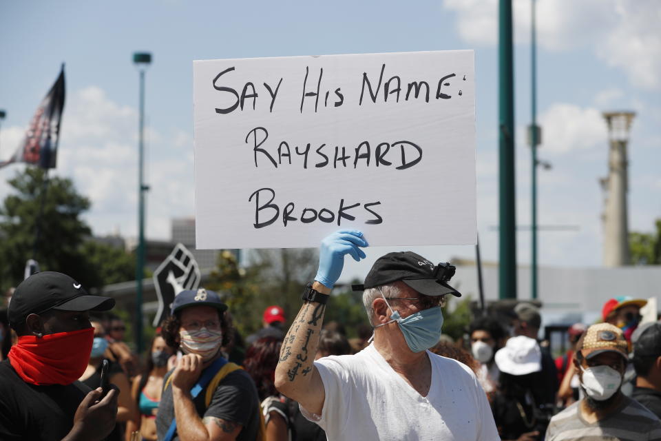 Protestors carry signs with Rayshard Brooks' name.