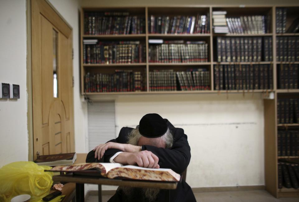 An Ultra-orthodox Jew leans on a religious Jewish text inside a Jerusalem synagogue