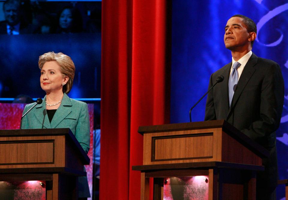 Then-senators Barack Obama and Hillary Clinton stand on stage before the start of their debate in Philadelphia on April 16, 2008.