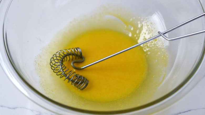 beaten egg yolks in clear mixing bowl with whisk